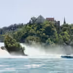 a boat on the water with Rhine Falls in the background